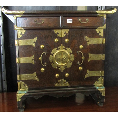 2583 - A small Korean cabinet in oak enclosed by two doors and two frieze drawers, with overlaid brass deta... 