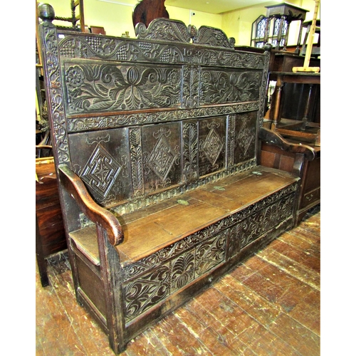 2699 - A 17th century and later box settle, with carved floral and fruiting vine detail, the crest dated 16... 