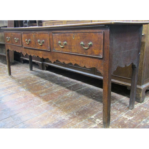 2728 - A Georgian dresser base with three drawers and shaped apron, 220cm long