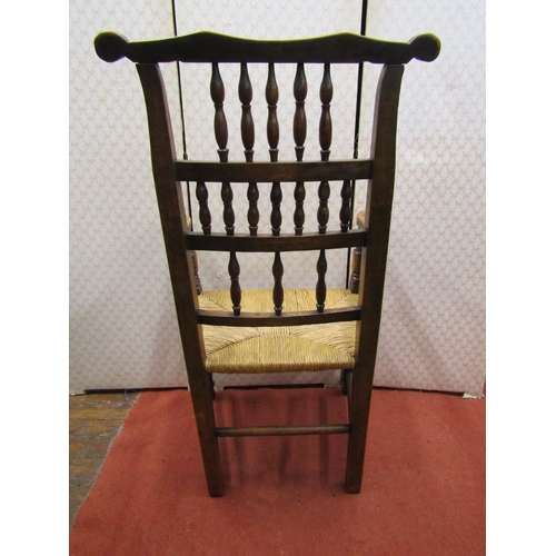 2767 - A Georgian ashwood spindle back elbow chair with rush seat on turned supports