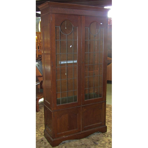 2329 - An Edwardian Arts & Crafts oak bookcase, freestanding and enclosed by two pairs of panelled doors, t... 