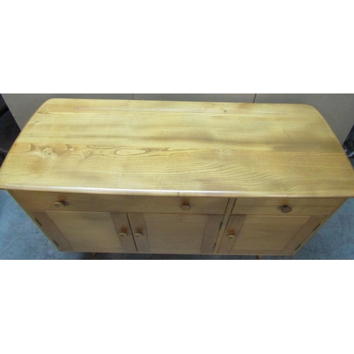 2398 - An Ercol light elm and beechwood dresser base, enclosed by three doors and two drawers, raised on sp... 