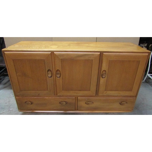 2399 - An Ercol light elm dresser enclosed by three doors and two drawers with dished handles, set on sheph... 