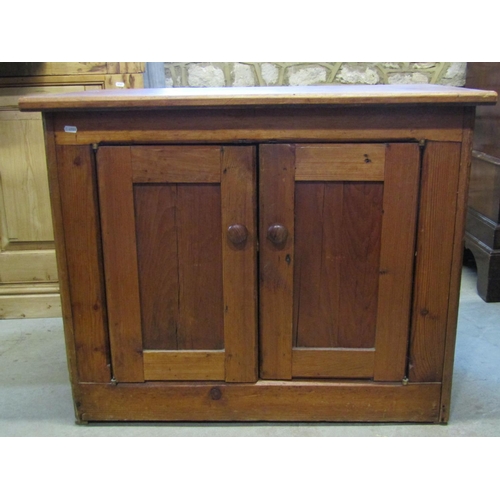 2415 - A rustic low stripped and waxed pine side cupboard enclosed by a pair of rectangular panelled doors,... 