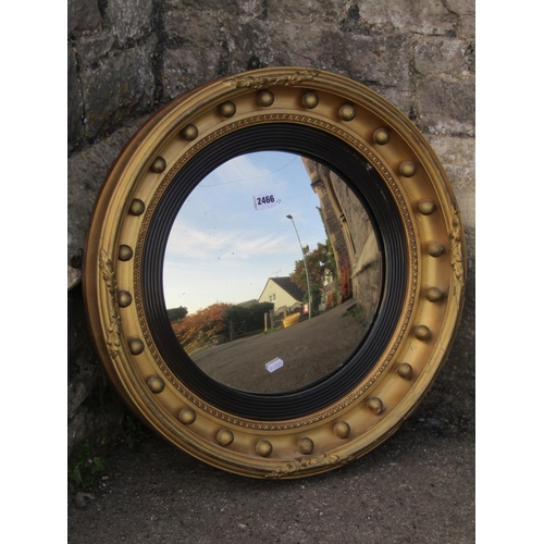 2466 - A 19th century convex wall mirror with ebonised reeded slip within a gilded frame with repeating bal... 