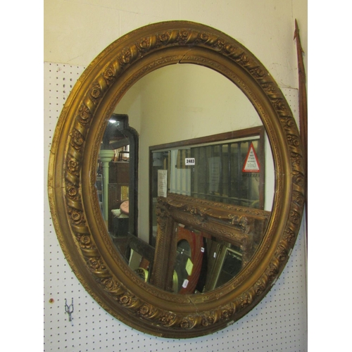 2483 - A large antique oval wall mirror with deep moulded cushioned frame with repeating rose and ribbon ba... 