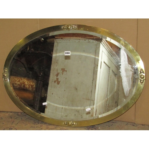 2484 - An early 20th century oval wall mirror with bevelled edge plate within a polished brass frame, 82 cm... 