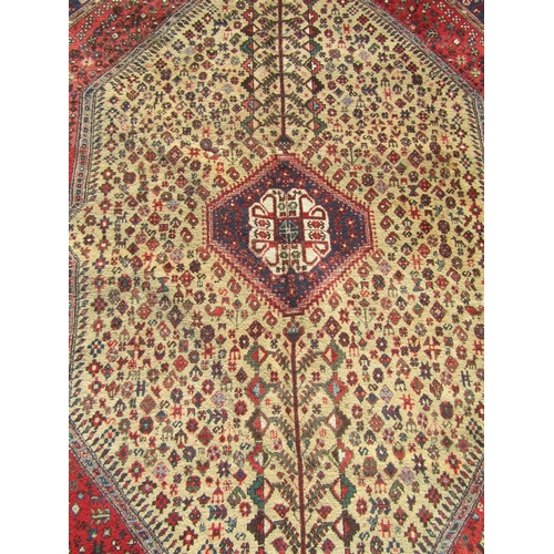 2522 - A Large Persian rug with an intricate design of dense floral, animal and symbolic motifs in tones of... 