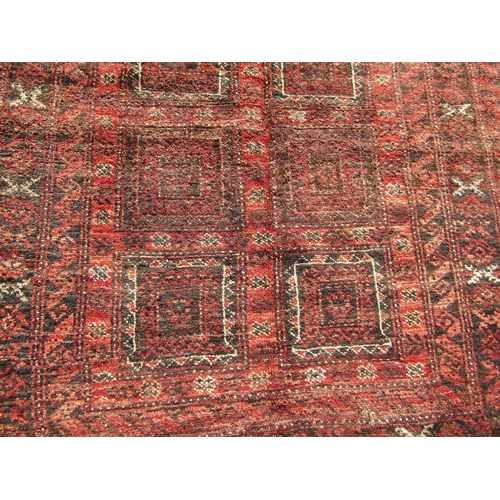 2528 - A North East Persian Turkoman rug with a central design of eighteen squares in deep tones of madder,... 