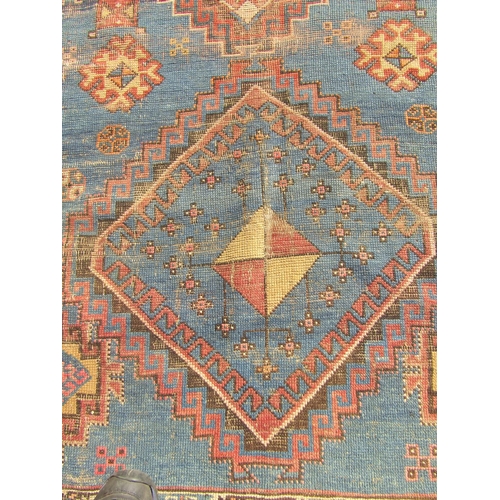 2532 - A Middle Eastern low-pile rug with two diamond medallions on a cobalt ground and a border of lobed a... 