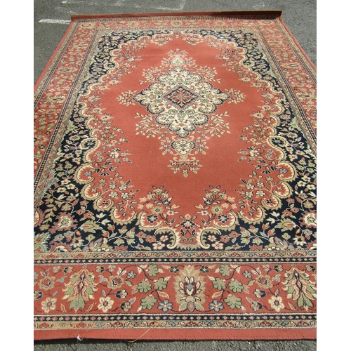 2533 - A Persian machine made carpet with a central scrolled medallion on a pale pink ground and running fl... 