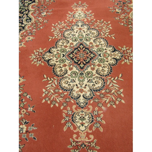 2533 - A Persian machine made carpet with a central scrolled medallion on a pale pink ground and running fl... 