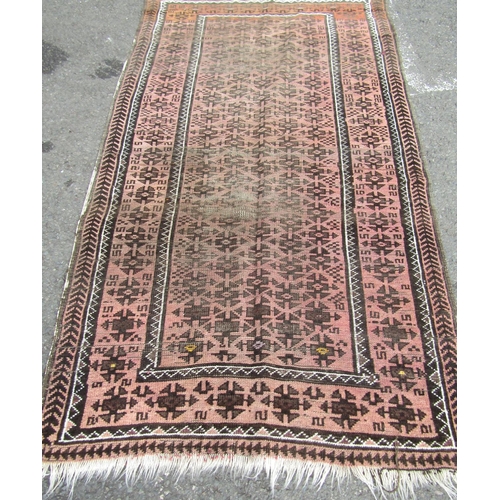 2537 - A worn Middle Eastern rug with repeated geometric design throughout in pale maroon and brown tones, ... 