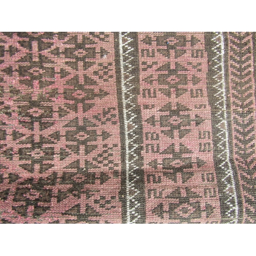 2537 - A worn Middle Eastern rug with repeated geometric design throughout in pale maroon and brown tones, ... 