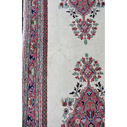 2545 - A Middle Eastern Runner with three central medallions and scrolling floral motifs in pink on an ivor... 