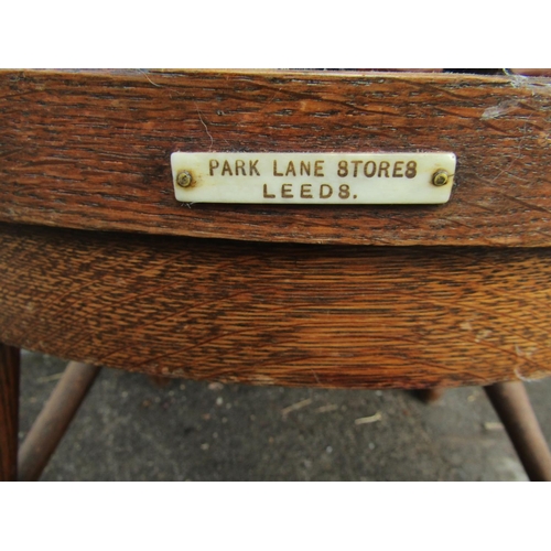 2349 - An early 20th century oak office desk chair with tapered spindle back, scrolled arms, pad seat, labe... 