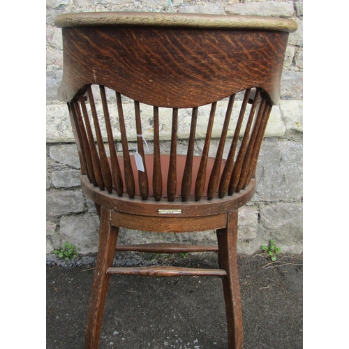 2349 - An early 20th century oak office desk chair with tapered spindle back, scrolled arms, pad seat, labe... 