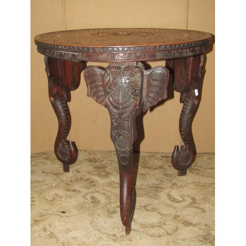 2431 - A Indian circular occasional table with profusely carved detail raised on three elephant head and tr... 