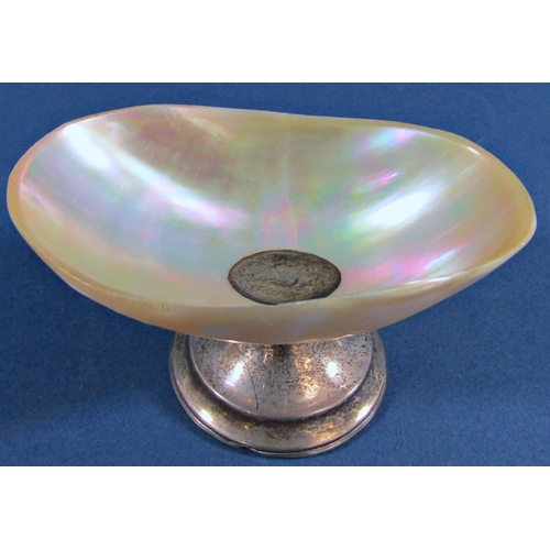 1210 - An iridescent shell salt bowl raised on a silver stand, a silver cylindrical scent bottle with overa... 