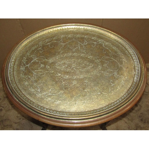 2191 - An Eastern oval engraved brass tray top occasional table raised on a mahogany stand with square cut ... 