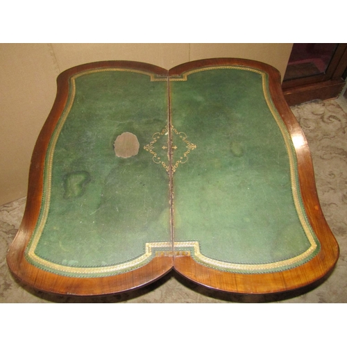 2197 - A walnut and figured walnut veneered fold over top card table with serpentine outline, raised on tur... 