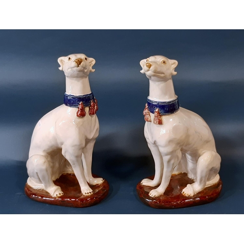 1007 - A pair of continental glazed figures of seated hounds wearing tasselled collars, 36cm high