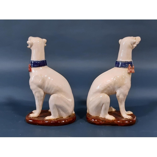 1007 - A pair of continental glazed figures of seated hounds wearing tasselled collars, 36cm high