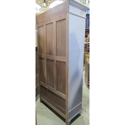 2293 - An oak armoire with painted finish enclosed by a stepped and arched bevelled edge mirror panelled do... 