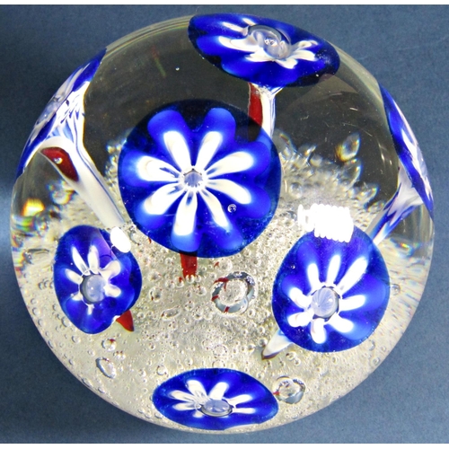 1169 - A single clear glass paperweight with seven stylised blue flowers emerging from a frothy, bubbly exp... 