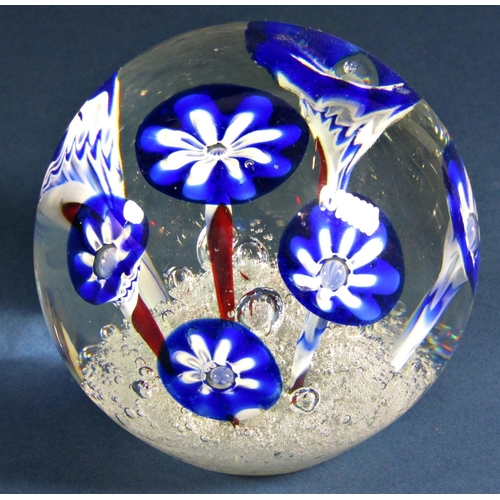 1169 - A single clear glass paperweight with seven stylised blue flowers emerging from a frothy, bubbly exp... 