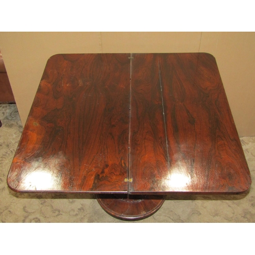 2319 - A 19th century rosewood foldover top tea table with scrolled frieze raised on a simple turned tapere... 