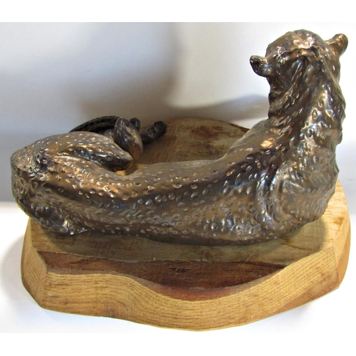 1678 - A bronze finished recumbent cheetah initialled B M below, resting on an oak block, 36cm wide approx.