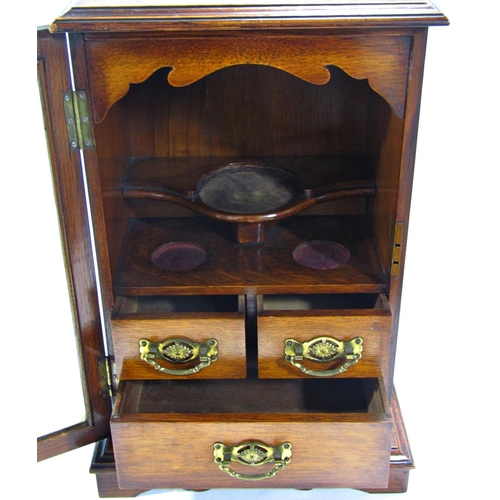 1705 - A Victorian oak smokers cabinet with a full glazed door revealing three drawers and three mixing pla... 