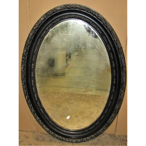 2477 - An Edwardian oval wall mirror, the ebonised frame with repeating bead and acanthus detail, 88 cm x 6... 