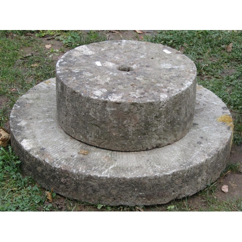 2053 - Two weathered carved natural stone mill stones of varying size, the largest 60 cm diameter x 10 cm t... 