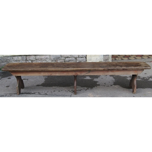 2186 - A vintage stained pine low bench with plank seat raised on three chamfered supports, 213 cm long (7f... 