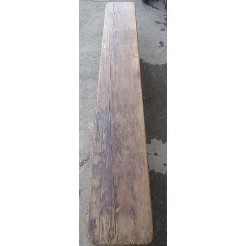 2186 - A vintage stained pine low bench with plank seat raised on three chamfered supports, 213 cm long (7f... 