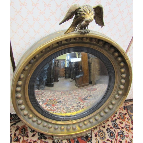 2804 - A Regency gilded convex wall mirror of usual form surmounted by an eagle, the lower platform with br... 