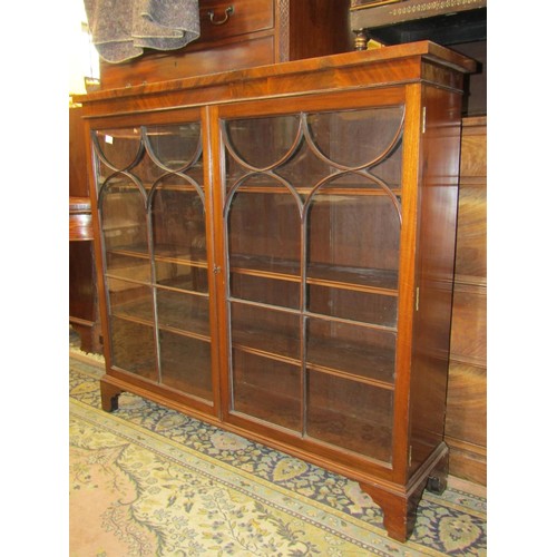 2695 - A mahogany enclosed bookcase in the Georgian style with glazed panelled doors, raised on bracket sup... 