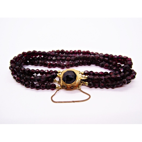 1404 - Four strand garnet bead bracelet with 14ct clasp set with a large rose-cut garnet