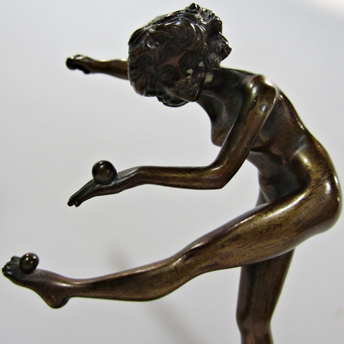 1737 - An early 20th century bronze naked female acrobat balancing balls on her hands and left foot, balanc... 