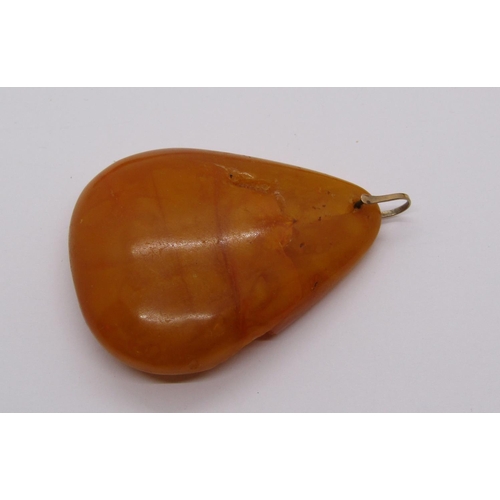 1409 - Large amber coloured pendant of organic form with yellow metal bale, 21.9g, together with a further ... 