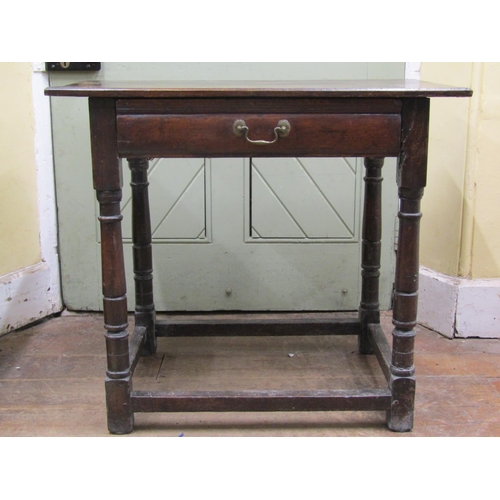 2612 - An 18th century oak side table the plank top raised on four turned supports and enclosing a frieze d... 