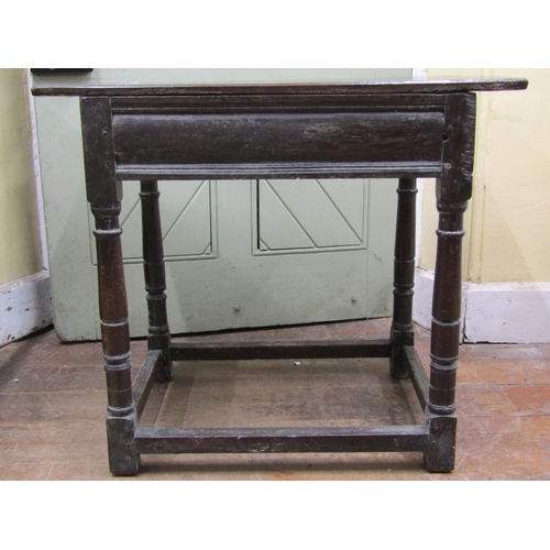 2612 - An 18th century oak side table the plank top raised on four turned supports and enclosing a frieze d... 