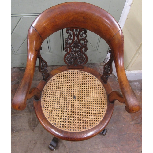 2665 - A Victorian walnut office chair with shoe shaped back over a circular cane work seat, with swivel ba... 