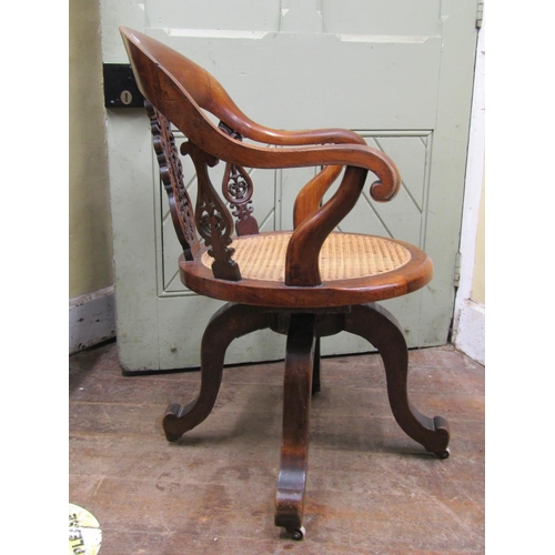 2665 - A Victorian walnut office chair with shoe shaped back over a circular cane work seat, with swivel ba... 