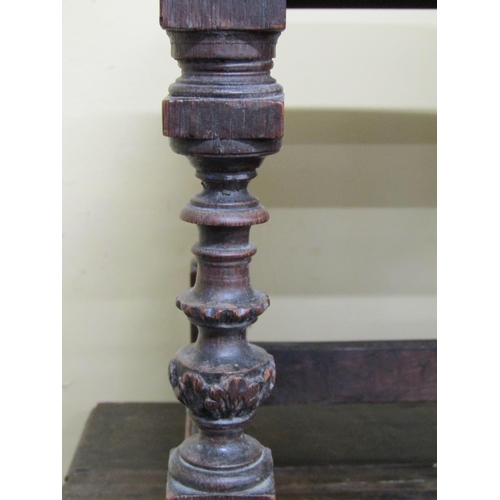 2679 - An antique oak stool with upholstered top raised on four turned and carved supports