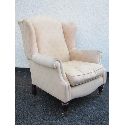 2543 - A Georgian style wing chair with scrolled arms, turned supports in a pale lemon ground upholstery