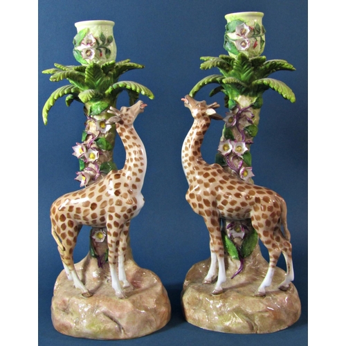 1065 - a pair of 19th century continental porcelain candlesticks in the form of giraffes beneath floral enc... 