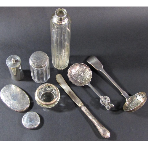 1203 - A mixed selection of silver including a tea strainer, pepper pot, glass bottles with silver lids/col... 